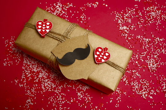 Father's Day greeting message with gift box  on red paper background. Happy fathers day concept. sticker in the form of black mustache.