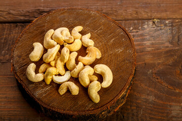 Cashew nuts scattered on a round board on a wooden table.