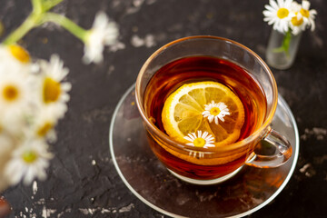 chamomile tea with lemon in a transparent cup on a black background. Breakfast concept, herbal tea.