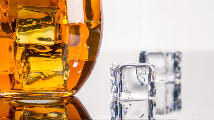 Glass of Alcohol Drink with Ice on white background. Whiskey or Brandy. Clear ice in cube shape. Frozen water. Ice maker. Fake or Artificial acrylic or plastic ice cubes.