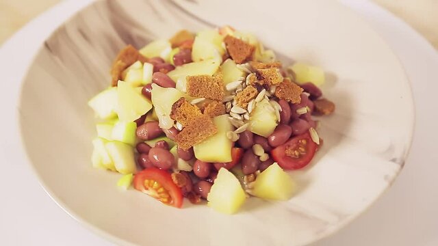 Thai vegetable salad with pineapple and croutons in a plate rotates in a circle