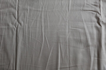 A nice crumpled fabric with creases of beige sand color can be a tablecloth or a sheet used as a background
