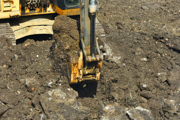 A image of the bucket on a track hoe actively excavating a construction site. 