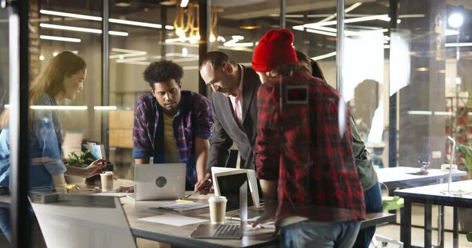 Young diverse creative team discussing plan details with experienced leader. Group of millennial developers chatting in office and brainstorming 4k footage