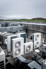 Square air-conditioning units on the roof with round fan grills. In background gradually receding...