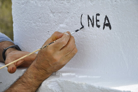 Mano Pintando Con Un Pincel Letras En Negro En Una Pared Blanca