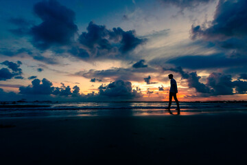Silhueta de um jovem andando em direção ao mar durante anoitecer em Serrambi.