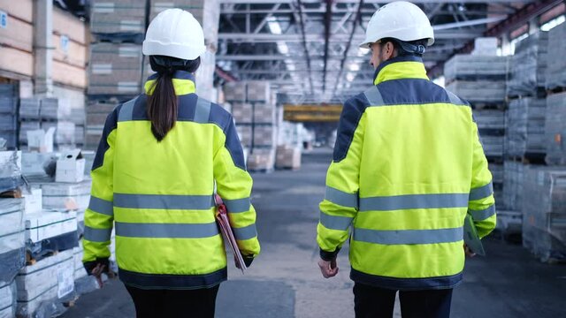 Follow footage of employees male and famale warehouse worker engineer in hard hat working. walking through logistics center warehouse factory construction site logistics architect businessman man