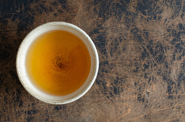 green puer in clay cup on abstract wooden background