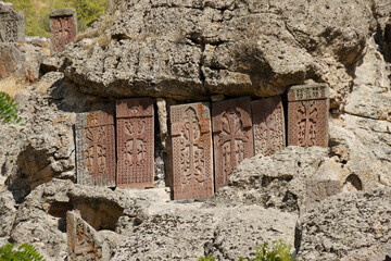 Intricately carved stone khatchkars stand on a rocky hillside at Geghard Monastery (Monastery of...