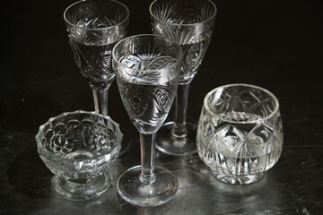 Set of crystal tableware with pure water on dark background. Transparent glasswares.
