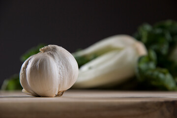 Garlic on wood cutting board with bok choy in the background