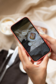 a woman takes photos of her breakfast with pudding on her phone