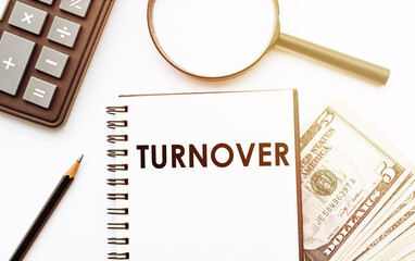 White notepad with the text of the TURNOVER on the background of dollars and office tools.