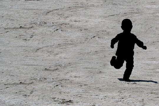 silhouette of a boy running with sand