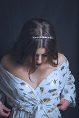 Mujer con vestido blanco y dorado en estudio.