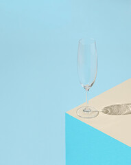 Empty champagne glass on pastel blue and beige background. Minimal abstract concept.