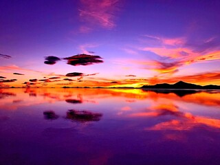 Magical sunrise sky over mysterious lake in desert. Incredible heaven clouds reflection in water. Surreal fantasy landscape alike alien planet.