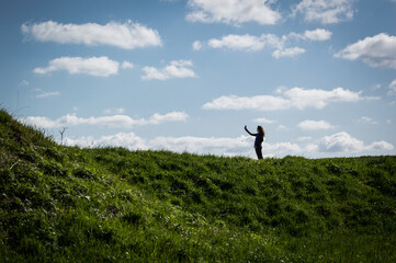 person in the grass taking a selfie and some clouds in the background