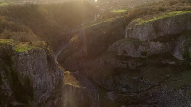 Aerial of Cheddar Gorge limestone rocks and road below with lensflare in Somerset, UK