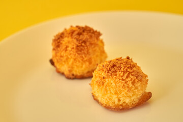 Coconut cookies on a white plate and on a yellow background.