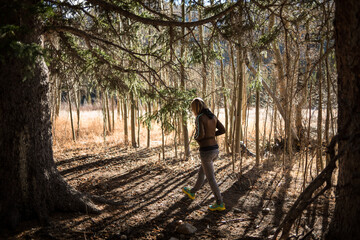 Woman Walking on Trail in Woods with Hands in Pockets Contemplative Amongst Aspen and Pine Trees