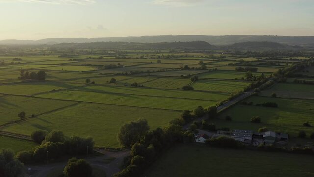 Aerial of magical sunlit green countryside fields of Somerset levels near Glastonbury, UK