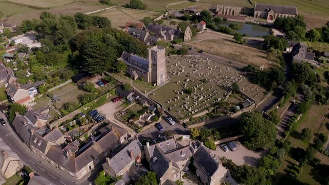 Aerial shot of traditional idyllic English village Abbotsbury, Dorset on a summer's day - ending on St Nicholas' Church and cemetery 
