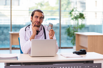 Young male medic holding banknote in the clinic