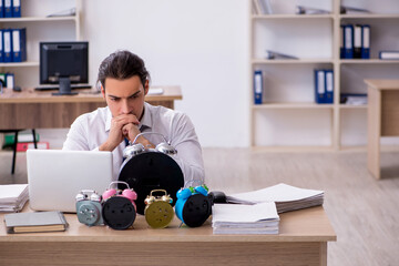 Young male employee afraid of missing deadline at workplace