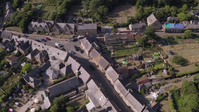 Aerial of rows of limestone cottages in traditional English village of Abbotsbury, Dorset on a summer's day