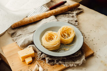 prepare mediterranean food at home. pasta with cheese, garlic and spices in stylish blue dish in bright kitchen with napkin.creative mess in the kitchen while cooking. vertical, selective focus