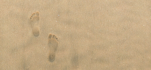 Footprints of a human in seashore sand with a selective focus on footprints . Copy space . Tipy view . Aerial