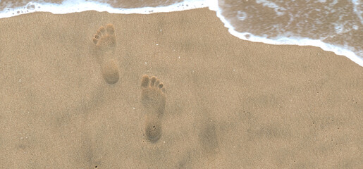 Footprints of a human in seashore sand with a selective focus on footprints . Copy space . Tipy view . Aerial