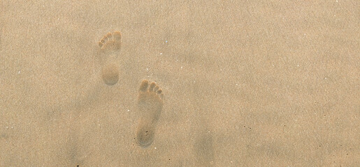 Fototapeta na wymiar Footprints of a human in seashore sand with a selective focus on footprints . Copy space . Tipy view . Aerial