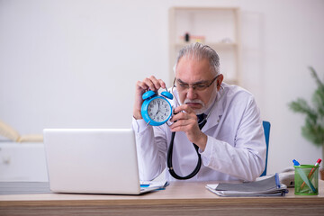Old male doctor in time management concept
