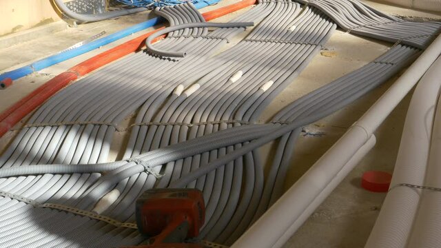 CLOSE UP: Plastic electricity tubing is laid across the first floor of a modern real estate project. Coils of colorful corrugated tubing are unwound across the floor of a house under construction.