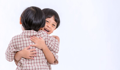 Twin boys hugging  on white background. Portrait of little son hugging brother or friend. I missing you. Full length happy boy embracing glad brother or friend while standing indoor. Positive meeting 