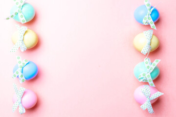 Easter egg hunt. Colorful egg with tape ribbon on pastel pink background in Happy Easter decoration. Traditional design in top view.