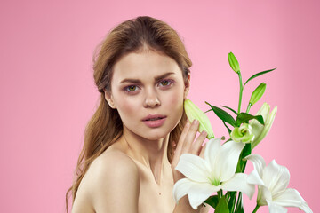 Obraz na płótnie Canvas Beautiful woman with flowers on pink background makeup portrait model