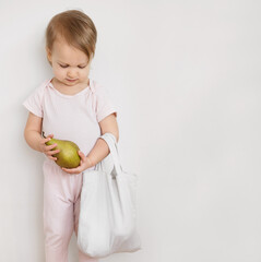 Happy child gives fruits from eco reusable textile bag. Plastic free and zero waste concept. Fresh...