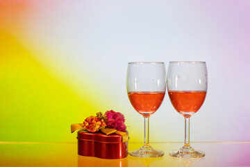 two glasses of red wine, gift box with colourful rosy background. Concept of romantic mother father valentine wedding day