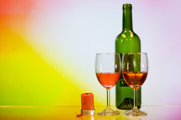 two glasses of red wine, bottle, candle with colourful rosy background. Concept of romantic mother father valentine wedding day
