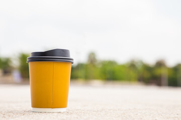 Obraz premium Disposable coffee cup on city park background.