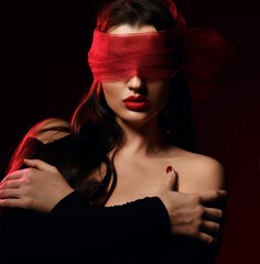 Portrait. Brunette woman vamp in off-shoulder dress and with her eyes covered with scarf, blindfold. Sex role play, games. Black background. Fashion, vogue, sexy stylish look for woman concept
