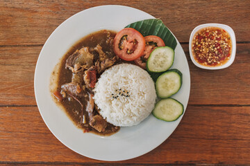 Thai stewed beef with rice served on white dish in the cafe.