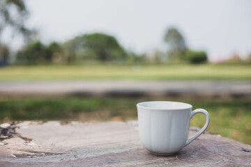 A selective focus picture of a cup of coffee on stone table in green garden