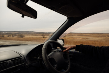 view from car window of field, sky and wildlife and blurred people hand behind the wheel. car trips local tourism. the real moment of hitchhiking. blog tourism content. selective focus