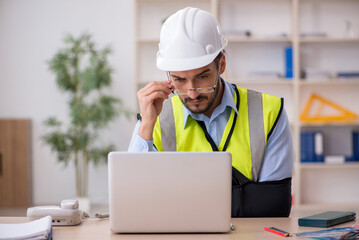 Young arm injured male architect working in the office