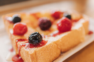 Dessert of toast bread with cherry and berry served on white dish.